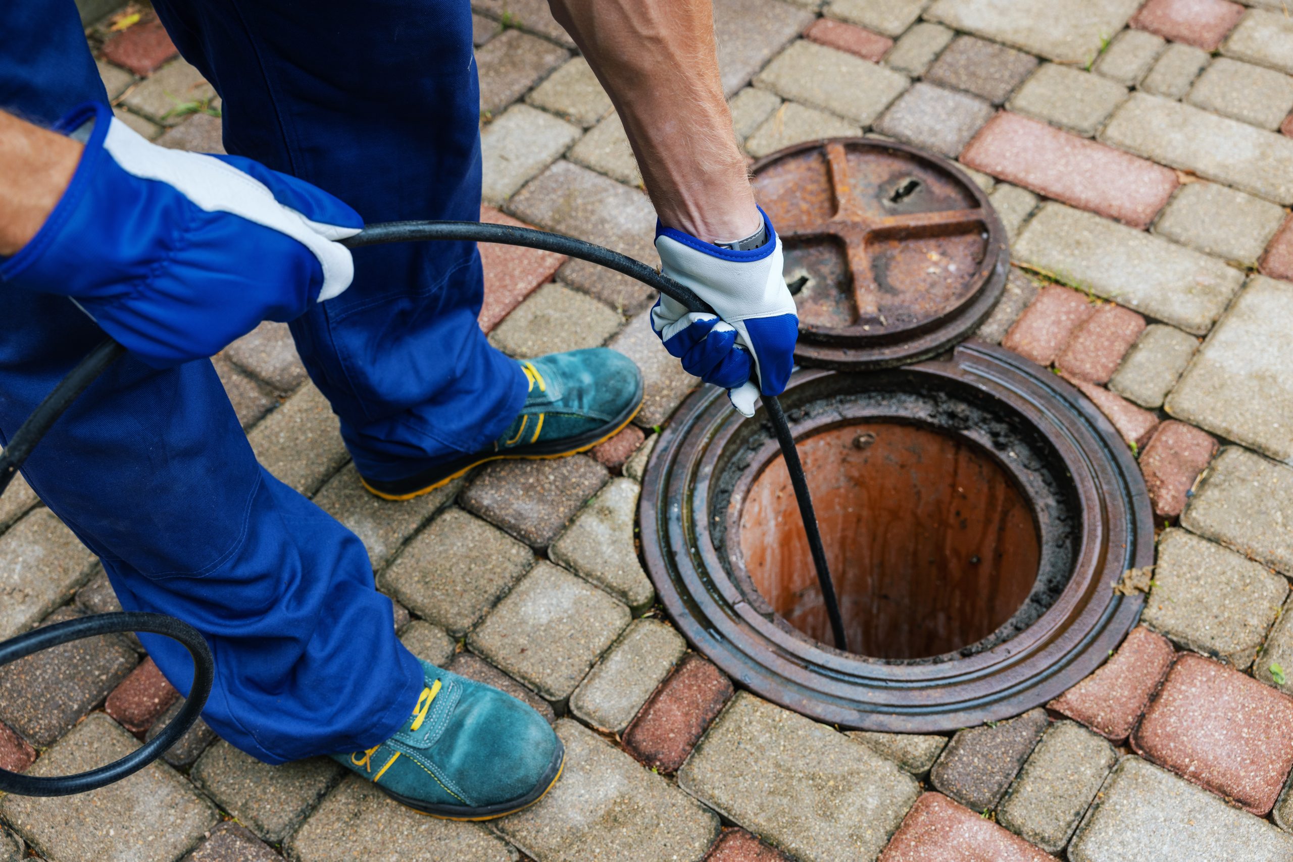 sewer cleaning service - worker clean a clogged drainage with hy